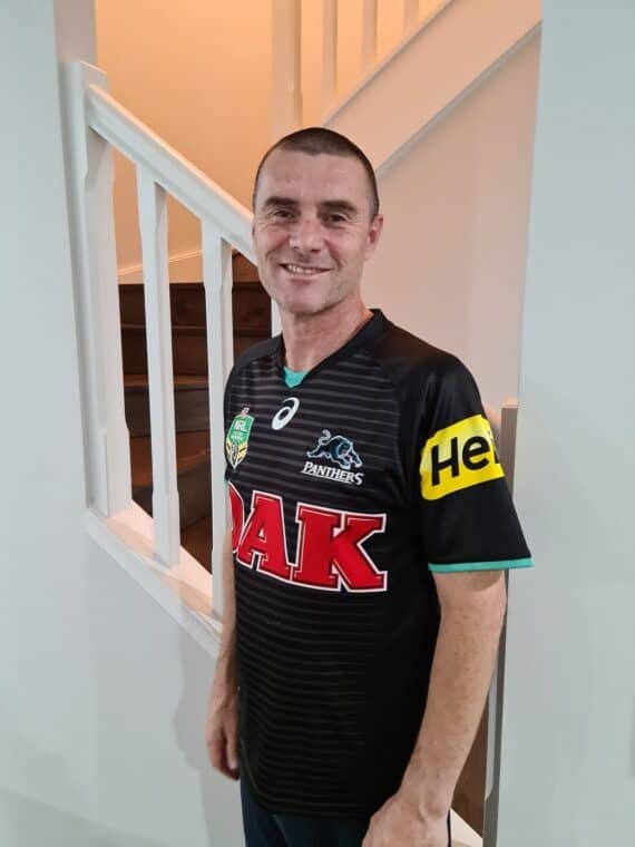A photo of a smiling man wearing a penrith panthers jersey